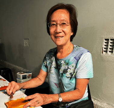 Volunteer smiling while preparing food at a community table.